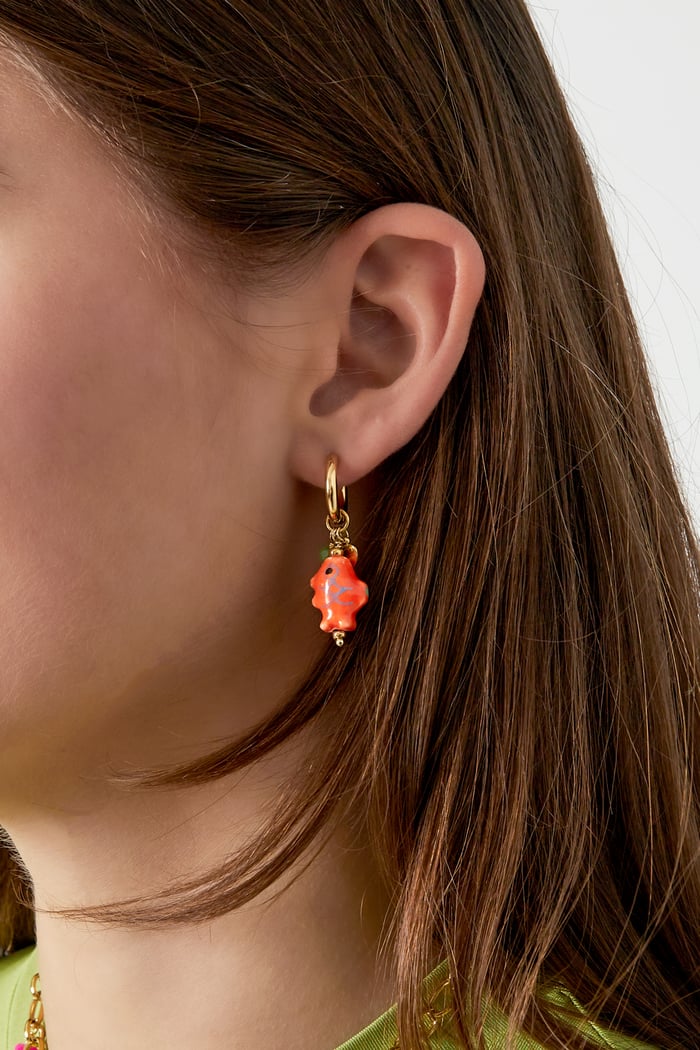 Model trägt die Ohrringe mit Fisch-Charm in Orange, die das Outfit perfekt ergänzen