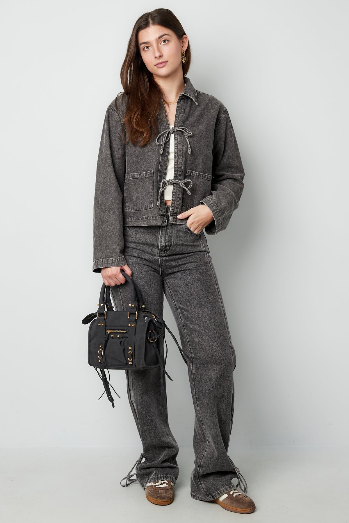 Model trägt die graue Jeansjacke mit Schleifen, passend zu einem trendigen Outfit