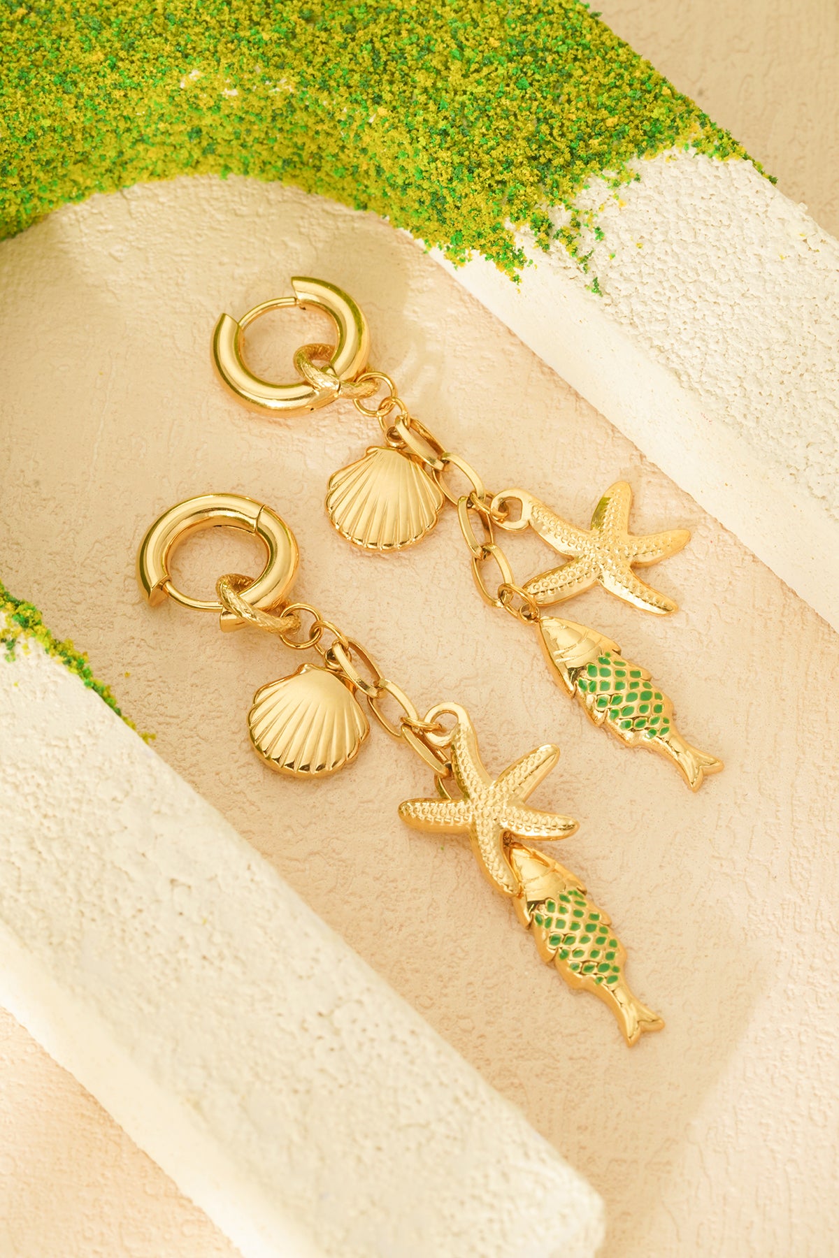 Detailaufnahme der Mini-Creolen in gold, versehen mit bezaubernden Muschel-, Seestern- und Fisch-Charm