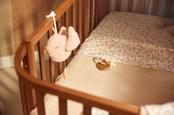 Der Anhänger ist an einem Babybett befestigt und spielt eine beruhigende Melodie für das Baby.
