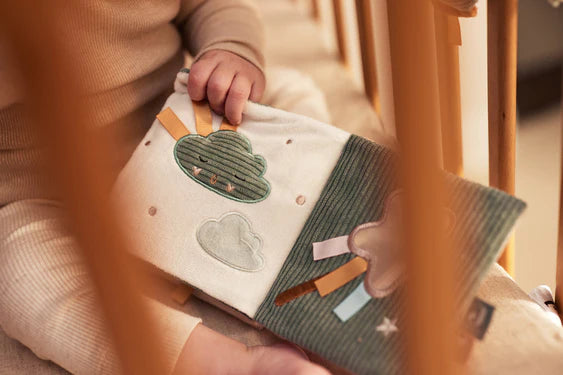 Baby spielt neugierig mit dem bunten Aktivitätsbuch Lovely Birds