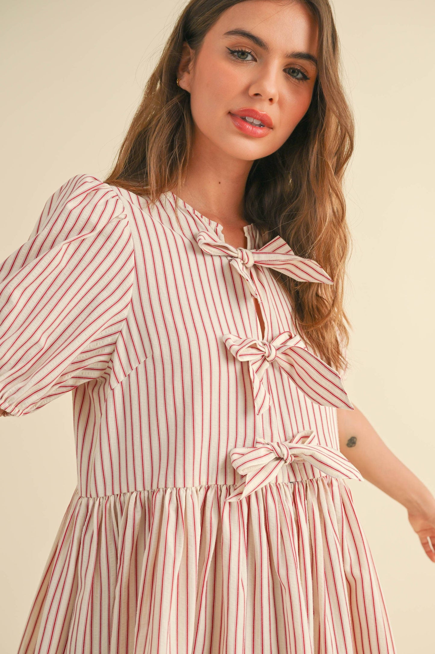 Verspieltes Kleid mit Schleifen vorne und Streifen – Modernes, gestreiftes Design mit süßen Schleifen vorne und Puffärmeln für einen frischen, sommerlichen Look.