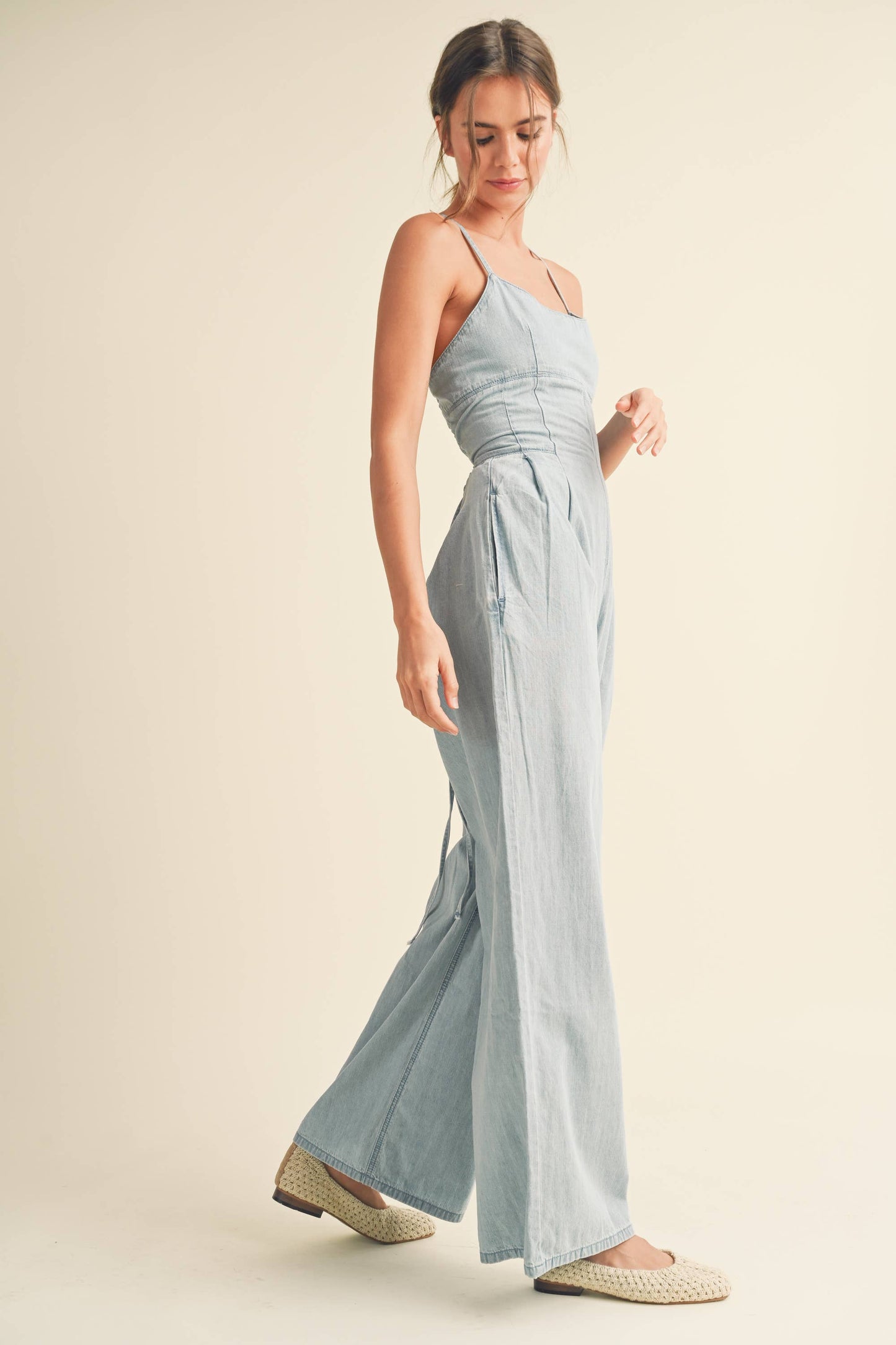Model trägt den Denim Overall mit langen Beinen, Spaghettiträgern und einem stylischen offenen Rücken