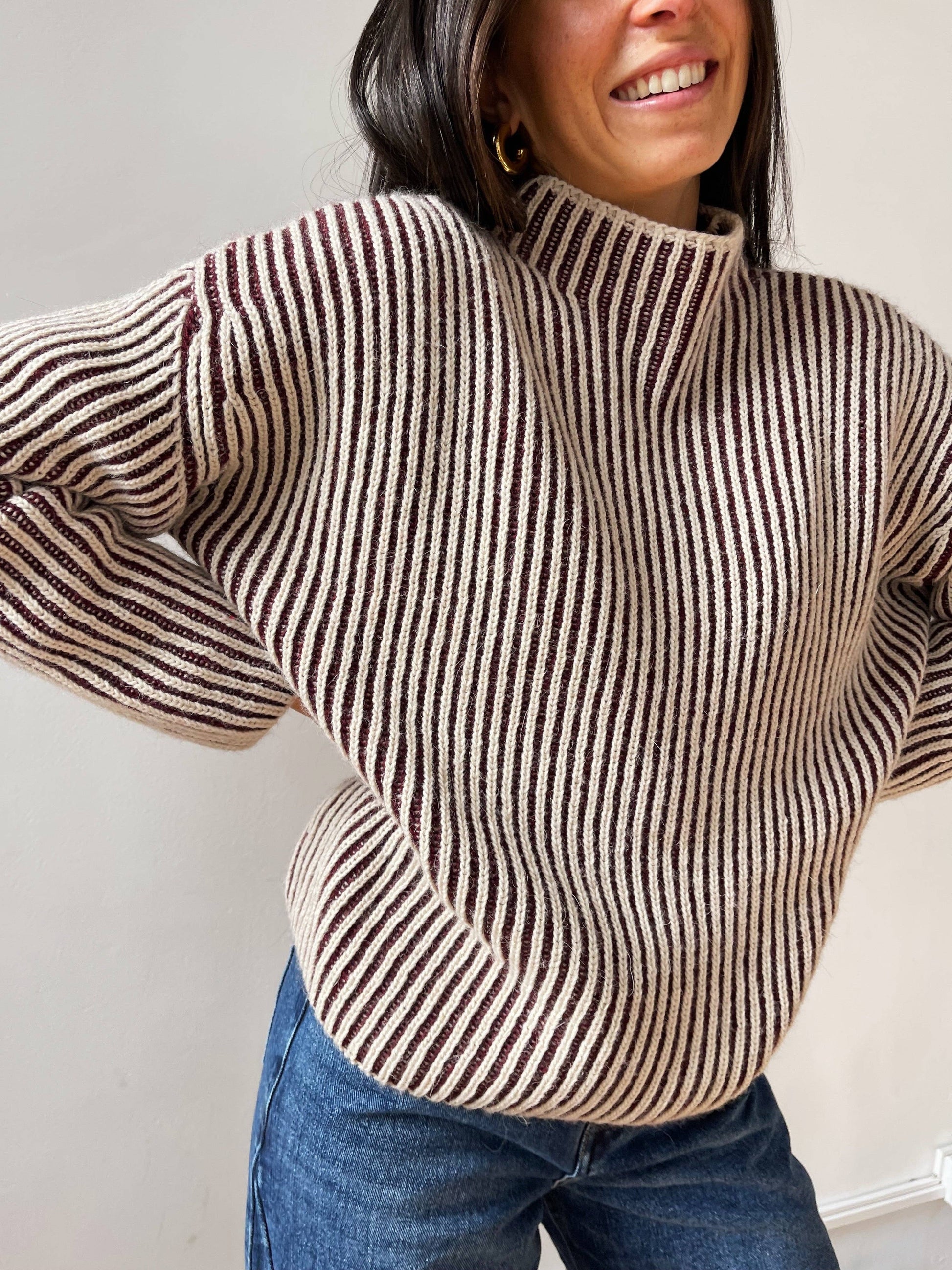 Nahaufnahme eines creme-burgunderfarbenen Strickpullovers mit Rippenstruktur