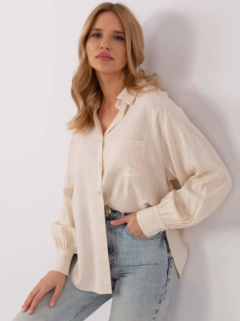 Modell trägt ein cremefarbenes Oversize-Hemd mit Puffärmeln und Jeans.